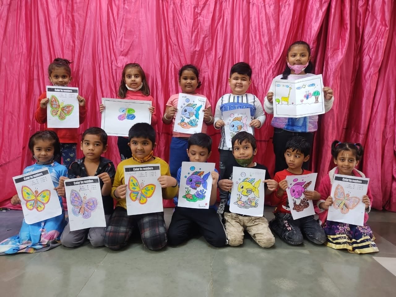 Young children proudly displaying their colourful artwork