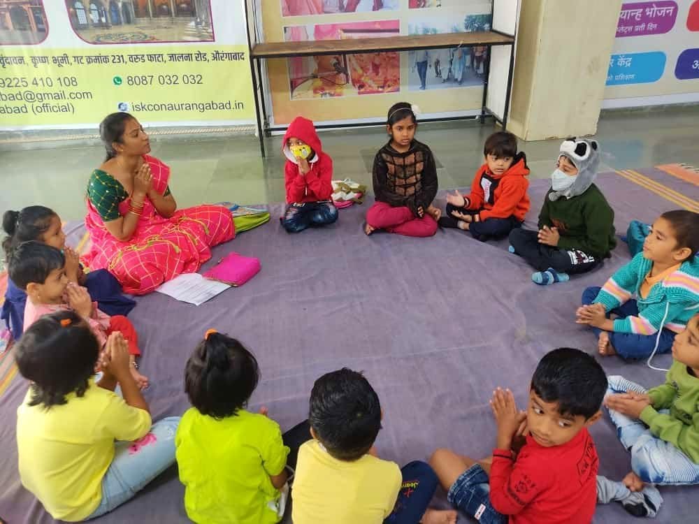 Young children seated in a devotional circle with their teacher