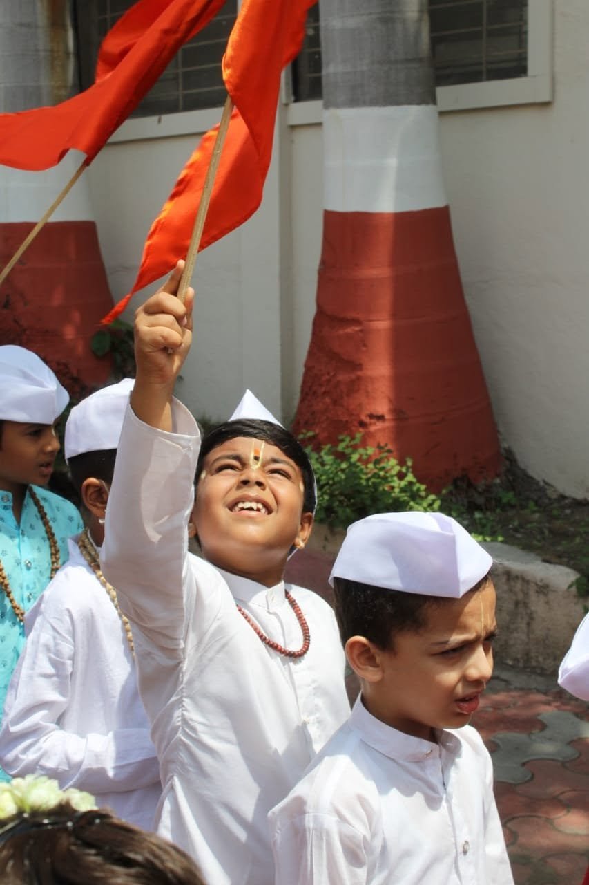 A child joyfully waving a saffron flag during a cultural celebration