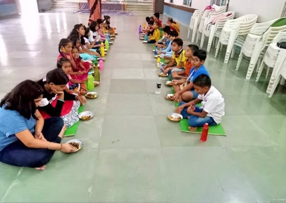 Children seated together and sharing prasadam after their programme